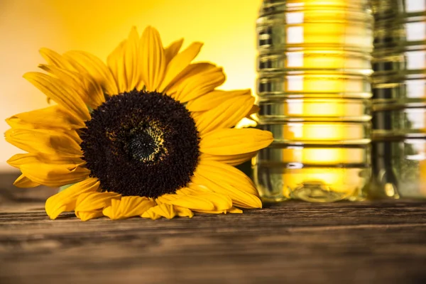 Huile de tournesol en bouteille, tournesol sur une table en bois — Photo