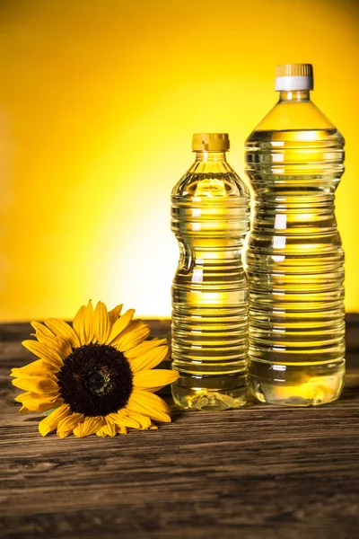 Aceite de girasol en una botella, girasol sobre una mesa de madera — Foto de Stock