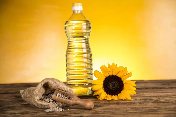 Aceite de girasol en una botella, girasol sobre una mesa de madera — Foto de Stock