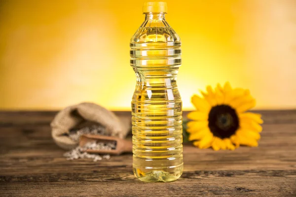 Aceite de girasol en una botella y flores de girasol y girasol se — Foto de Stock