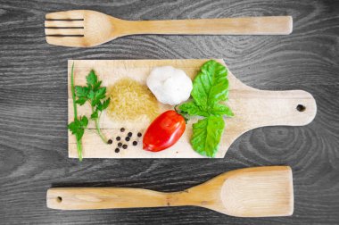 Taze domates, fesleğen, sarımsak, maydanoz, biber ve pirinç ahşap çatal tahta koyu ahşap arka plan ile bir kesme tahtası üstüne