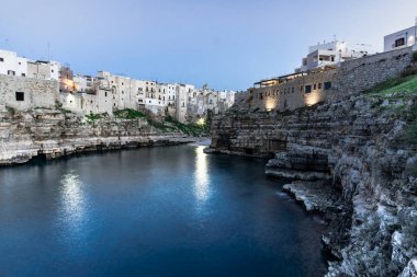 Polignano bir Mare, Puglia - İtalya. Arka planda Bastione di Santo Stefano ve Lama Monachile plaj ile Cala Paura körfezinde gün batımı