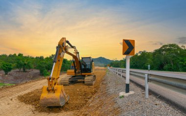 Backhoe yol inşaatında taş yığınları üzerinde çalışıyor.