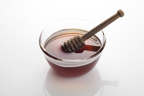 Bowl of Fresh Raw Golden Yellow Honey with a Brown Wooden Dipper 