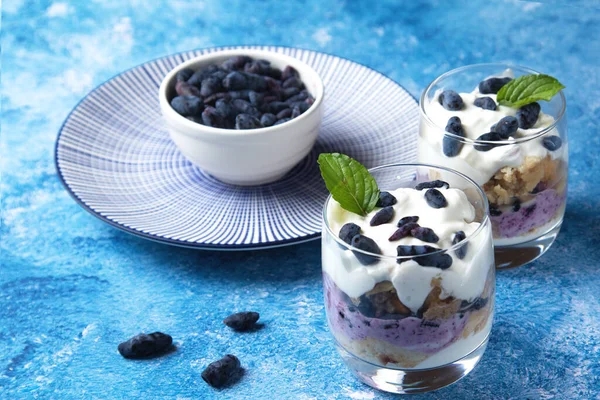 Hanımeli, cheesecake, kek meyveli kek, kek. Mavi arka planda iki bardak ve bir tabak dut.