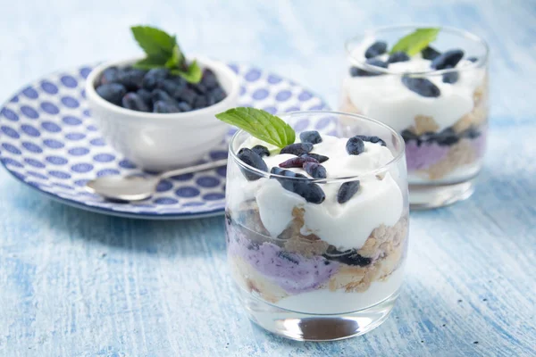 Hanımeli, peynirli kek, browni meyveli kek. İki bardak ve bir tabak hanımeli çileği mavi arka planda duruyor.