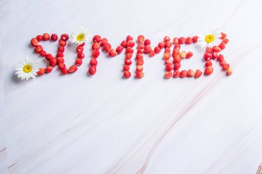 Yaz kelimesi arka planda yabani çileklerden yayılıyor.