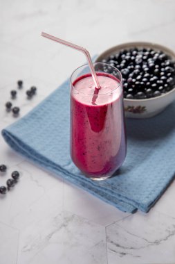 Diyet, cam bardakta böğürtlen suyu içer, pipetle birlikte beyaz tabak, açık arkaplanlı, mavi peçeteli.