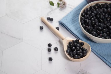 Hafif bir arka planda böğürtlenli ahşap bir kaşık, mavi bir peçetede iki bardak yaban mersinli meyve suyu var. Kopyalama alanı