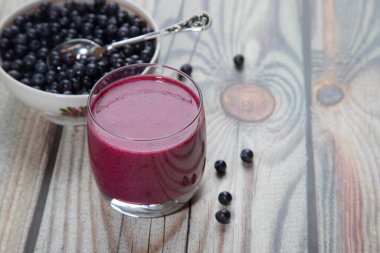 Ahşap bir arka planda yaban mersinli bir tabak ve diyet içeceği olan bir bardak yaban mersini püresi var. Kopi Spey için yer