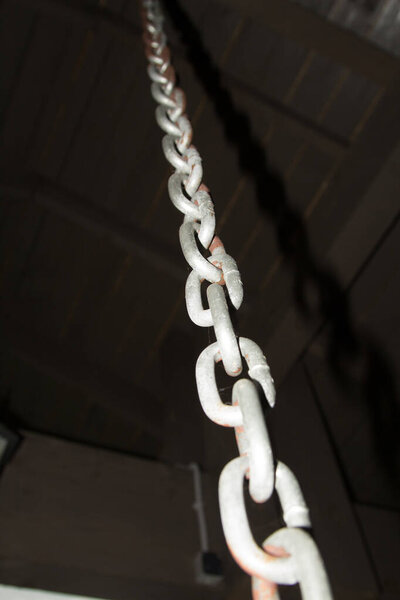 A large silver chain suspended from the dark ceiling