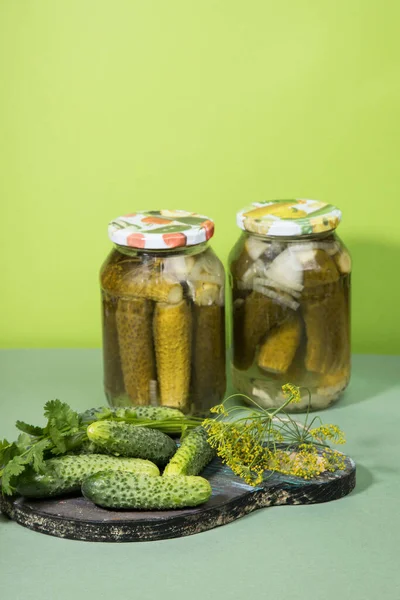 Two cans of pickles and gherkins. Pickled pickles on a wooden chopping Board with herbs. Vertical orientation