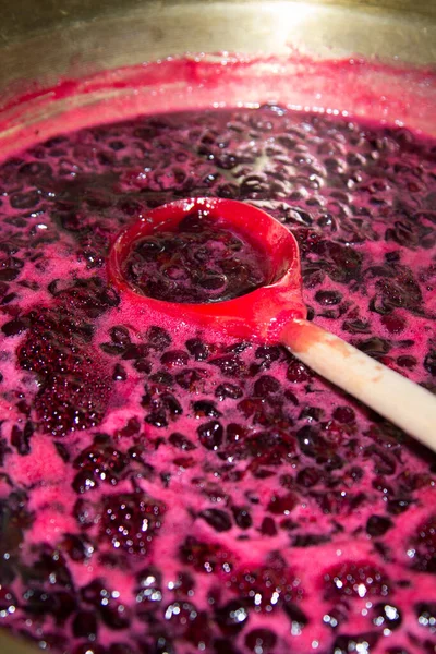 Frenk üzümü reçelini karıştırmak için bakır bir leğende tahta bir kaşık kullan. Dikey düzenleme