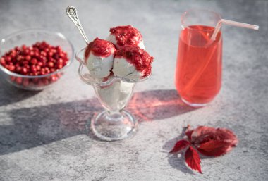 Kırmızı yaban mersinli kombu çayı ve cam kasede böğürtlenli vejetaryen dondurması, masada sonbahar yaprakları. Yatay yönelim