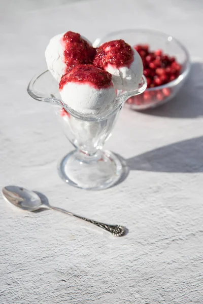 Arka planda üç top dondurma ve böğürtlen reçeli, cam kasede böğürtlen, masada güneş gölgeleri. Dikey yönelim
