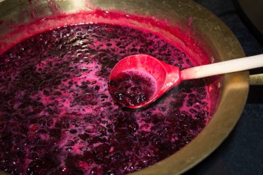 Evde, siyah frenk üzümü reçeli bakır bir leğende pişirilir ve tahta bir kaşıkla karıştırılır.