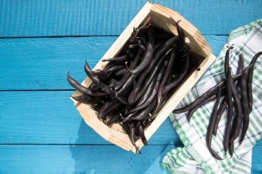 Ahşap mavi arka plandaki ahşap bir kutuda bulunan kuşkonmaz fasulyesi tohumları sebze proteinlerinin kaynağıdır. Sağlıklı beslenme kavramı. Kopyalama alanı