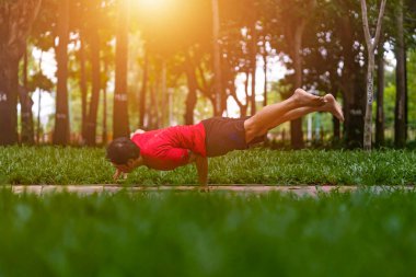 Genç Asyalı adam terini siliyor ve parkta yoga egzersizleri yapıyor. Yoga konsepti.