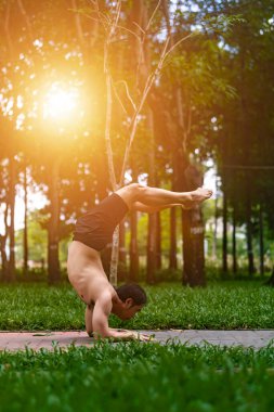 Genç Asyalı adam terini siliyor ve parkta yoga egzersizleri yapıyor. Yoga konsepti.