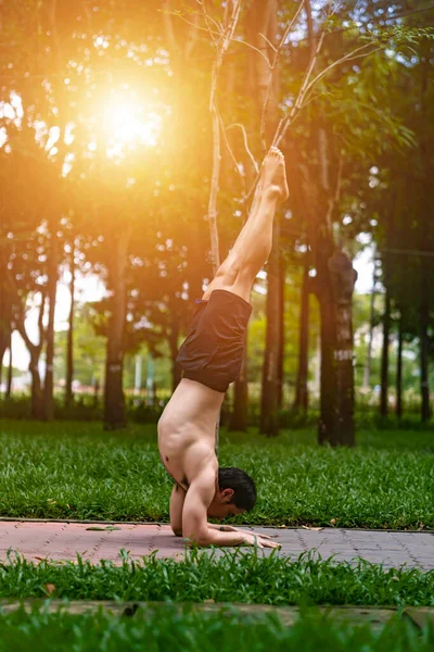 Young asian man are wiping sweat and doing yoga exercises in park. Yoga concept.