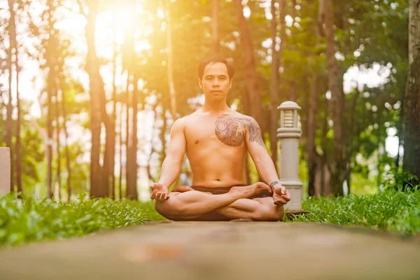 Young asian man are wiping sweat and doing yoga exercises in park. Yoga concept.