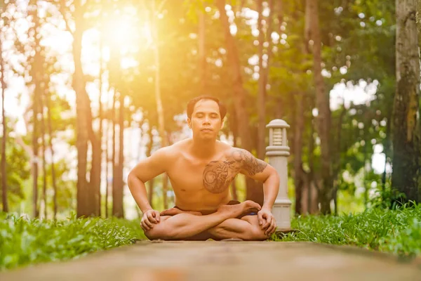 Young asian man are wiping sweat and doing yoga exercises in park. Yoga concept.