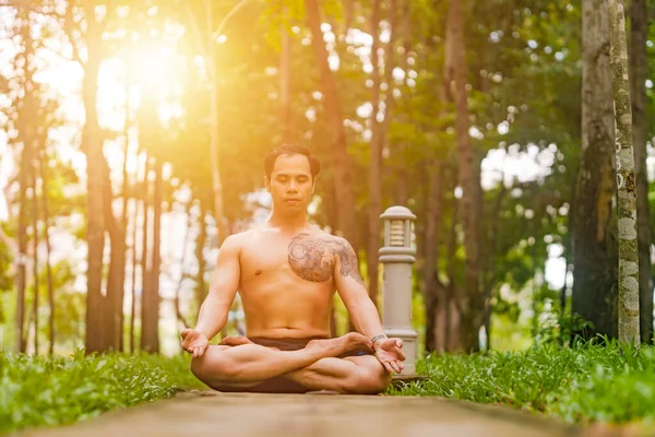 Young asian man are wiping sweat and doing yoga exercises in park. Yoga concept.