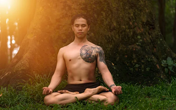 Young asian man are wiping sweat and doing yoga exercises in park. Yoga and zen concept.