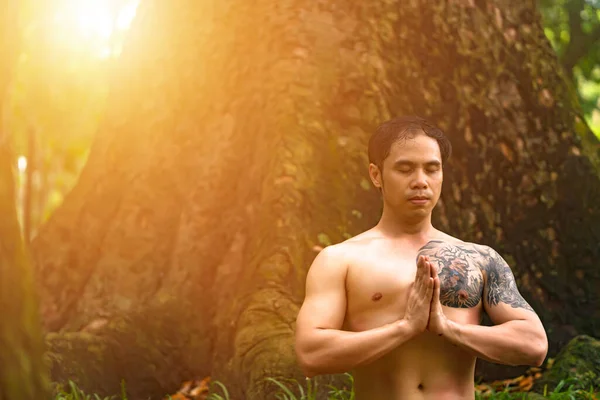 Young asian man are wiping sweat and doing yoga exercises in park. Yoga and zen concept.