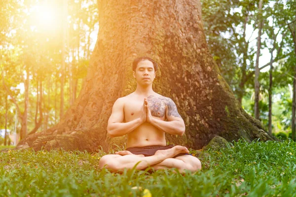 Young asian man are wiping sweat and doing yoga exercises in park. Yoga and zen concept.