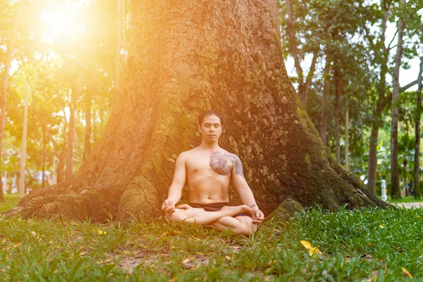 Young asian man are wiping sweat and doing yoga exercises in park. Yoga and zen concept.