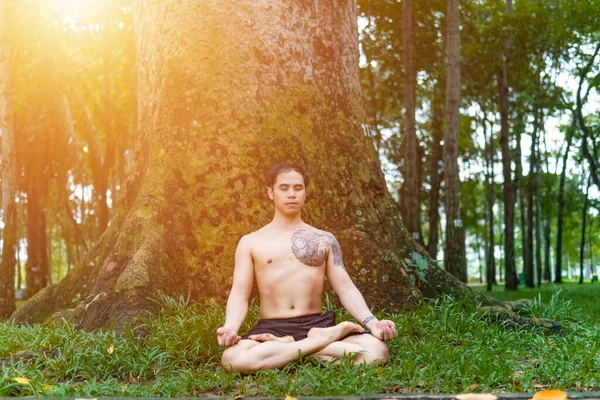 Young asian man are wiping sweat and doing yoga exercises in park. Yoga and zen concept.