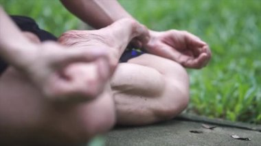 Ellerinizi kapatın. Asyalı adam dışarıda yoga yapıyor. Egzersiz yapan adam doğa arka planında fitness yaşam kulübü için hayati önem taşıyor ve meditasyon yapıyor. Sağlıklı ve Yoga Konsepti. Seçici odak.