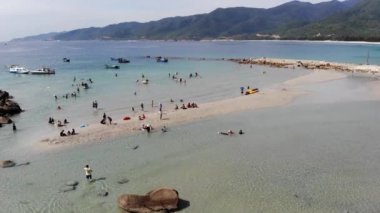 Binh Hung adasının turistlerle, balıkçı tekneleriyle, balıkçı köyleriyle ve yüzen botlarıyla Ninh Thuan eyaletinde deniz ürünleri yetiştiren sallarla dolu havadan görünüşü, Vietnam
