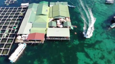 Binh Hung adasının turistlerle, balıkçı tekneleriyle, balıkçı köyleriyle ve yüzen botlarıyla Ninh Thuan eyaletinde deniz ürünleri yetiştiren sallarla dolu havadan görünüşü, Vietnam