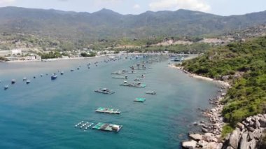 Binh Hung adasının turistlerle, balıkçı tekneleriyle, balıkçı köyleriyle ve yüzen botlarıyla Ninh Thuan eyaletinde deniz ürünleri yetiştiren sallarla dolu havadan görünüşü, Vietnam
