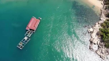 Binh Hung adasının turistlerle, balıkçı tekneleriyle, balıkçı köyleriyle ve yüzen botlarıyla Ninh Thuan eyaletinde deniz ürünleri yetiştiren sallarla dolu havadan görünüşü, Vietnam