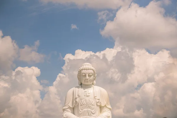 佛像后面高高的座上庄严的白色佛像是蓝天 白云密布 精神和宗教概念 — 图库照片