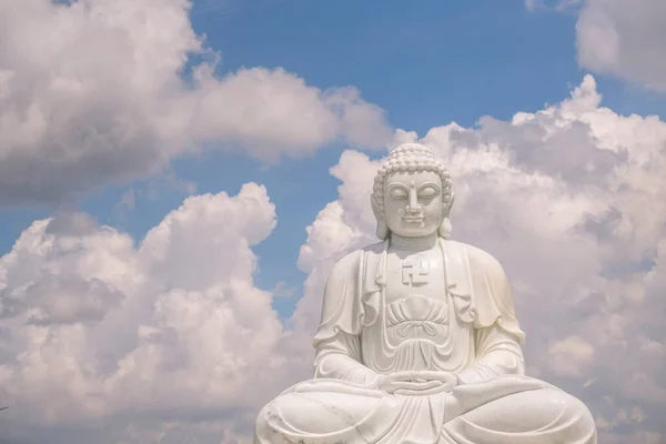 佛像后面高高的座上庄严的白色佛像是蓝天 白云密布 精神和宗教概念 — 图库照片