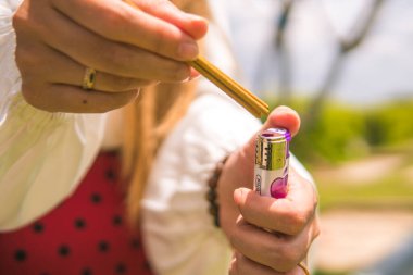 Bir kadının elinin tütsü yaktığı yakın plan. Arka plan bulanık, tanımlanamayan bir mezar.