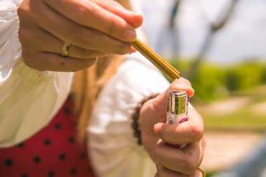 Bir kadının elinin tütsü yaktığı yakın plan. Arka plan bulanık, tanımlanamayan bir mezar.