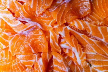 Taze çiğ somon balığı bıçakla kesiliyor ve kesme tahtasının üzerinde yatıyor. Japon somon balığı sashimi. Seçici odak.