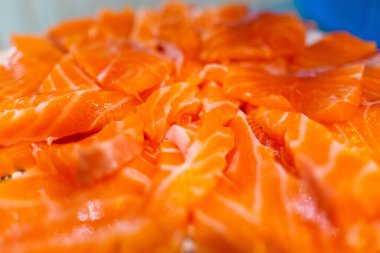 Taze çiğ somon balığı bıçakla kesiliyor ve kesme tahtasının üzerinde yatıyor. Japon somon balığı sashimi. Seçici odak.