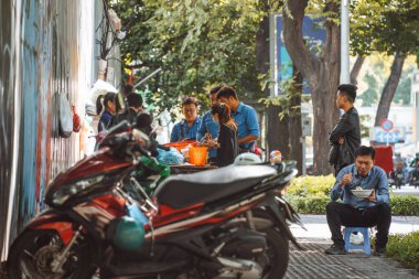 Saigon, Vietnam - 4 Temmuz 2020: Saigon (Ho Chi Minh City) sokakları, insanların yemek taşıyan bir arabanın kaldırımında kahvaltı ettikleri yer..