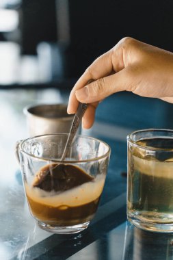 Kahveyi karıştıran bir kadının yakın plan elleri, Vietnam stili süt damlayan bir kahve. Seçici Odaklanma. İçki ve seyahat konsepti