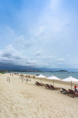 Mui Ne, Vietnam - 23 Temmuz 2020: Beyaz kumsalda şezlonglar ve açık mavi gökyüzünde beyaz şemsiyeli Muine Körfezi Resort, Mui Ne, Phan Thiet şehri, Binh Thuan, Vietnam