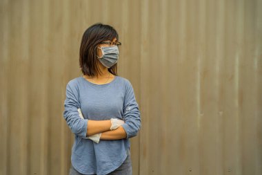 Grip ve virüsü korumak için yüzüne koruyucu hijyen maskesi takan Asyalı genç çekici bir kadın. Açık kahverengi arka planda enfekte olmuş kadın portresi. Covid19 ve Coronavirus