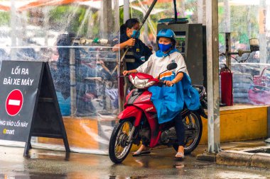 Ho Chi Minh şehri, Vietnam - 08 Ağustos 2020: Yerel halk Emart süpermarketinden alışveriş yapıyor, tıbbi maskeler takıyor, yağmurda motosiklet sürüyor ve Covid-19 salgınında sosyal mesafeyi koruyorlar.