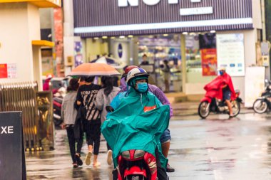 Ho Chi Minh şehri, Vietnam - 08 Ağustos 2020: Yerel halk Emart süpermarketinden alışveriş yapıyor, tıbbi maskeler takıyor, yağmurda motosiklet sürüyor ve Covid-19 salgınında sosyal mesafeyi koruyorlar.