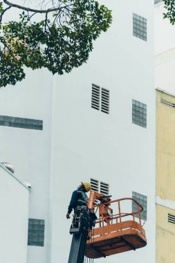 Ho Chi Minh şehri, Vietnam - 6 Ağustos 2020: Saigon, Vietnam 'da çalışan bir grup insan için turna kamyonu yolda, Vietnamlı işçiler yağmur mevsiminde yağmur mevsiminde ağaç dallarını kesmek için buharlı kaldırma üzerinde çalışıyorlar.